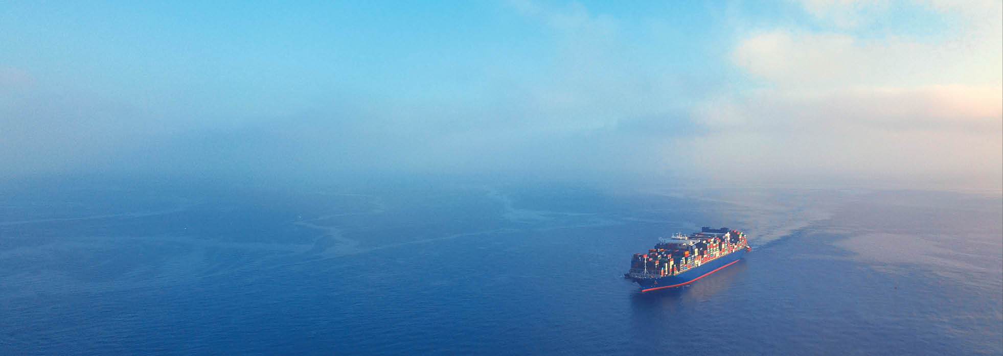 High angle view of a cargo ship approaching a transhipment hub in the Mediterranean region on a sunny day.